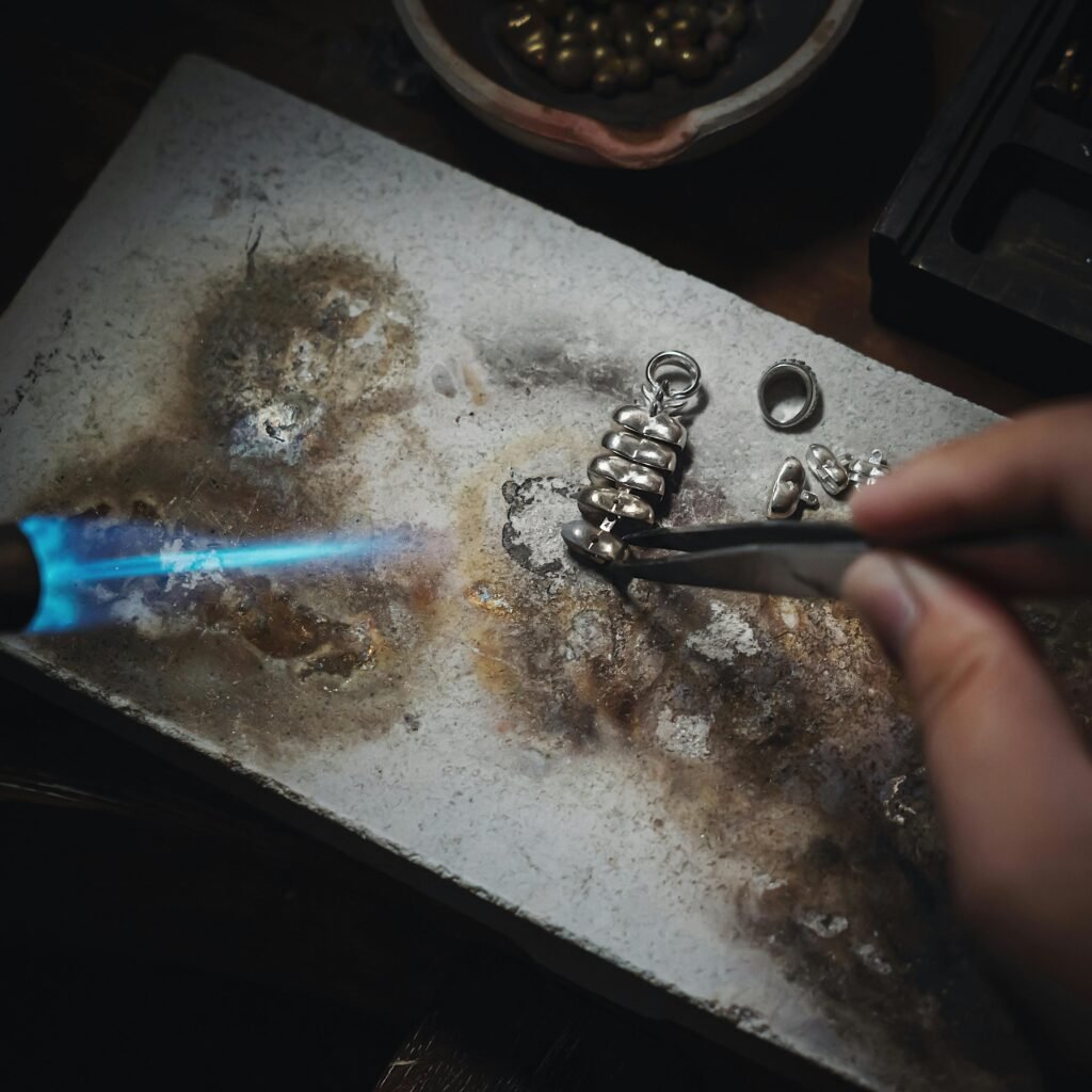 Artisan meticulously working with silver and flame to create handmade jewelry.